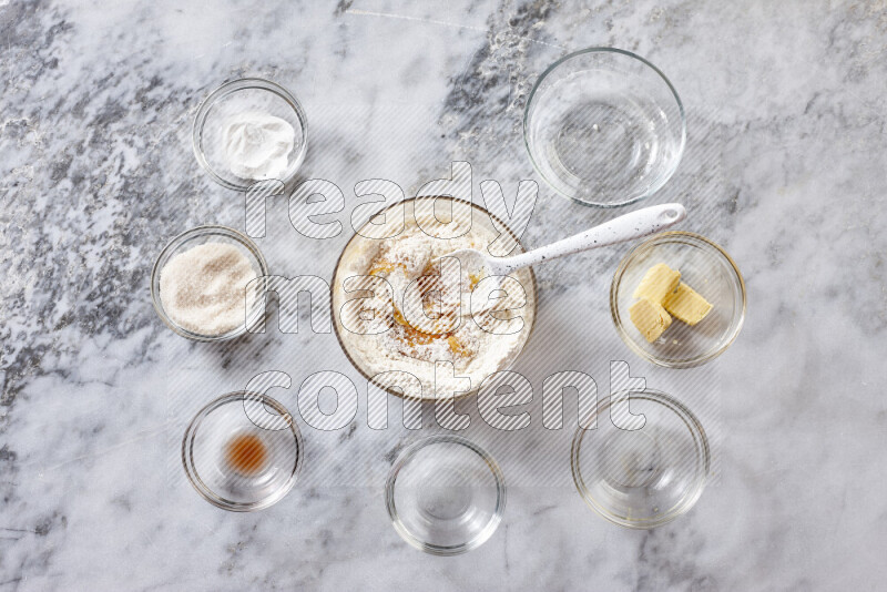 كوكيز خطوة بخطوة بمكوناتها، الدقيق، الزبدة، السكر البني، البيض، الفانيليا، السكر الأبيض، رقائق الشوكولاتة وصودا الخبز على خلفية رخام رمادي