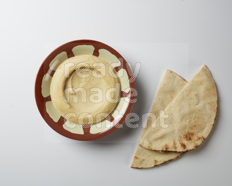 Plain hummus in a traditional plate on a white background