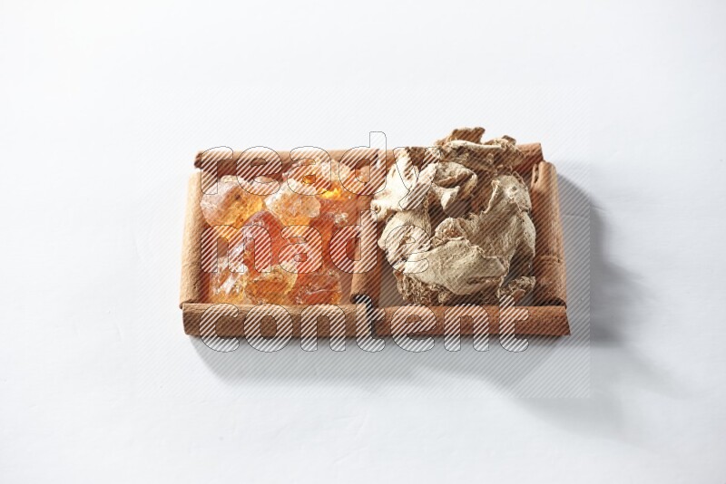 مربعان من أعواد القرفة ممتلئان بالزنجبيل المجفف والصمغ العربي علي خلفية بيضاء