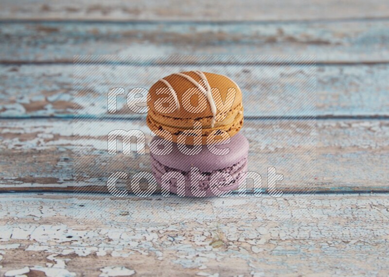 45º Shot of of two assorted Brown Irish Cream, and Purple Blueberry macarons  on light blue background