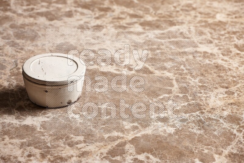 A white pottery bowl on beige marble background