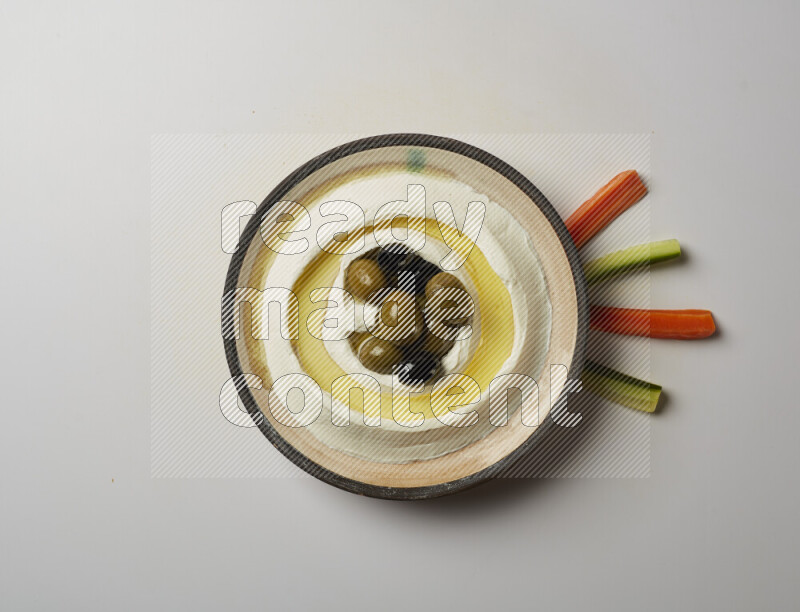 Lebnah garnished with whole black olives in a pottery plate on a white background