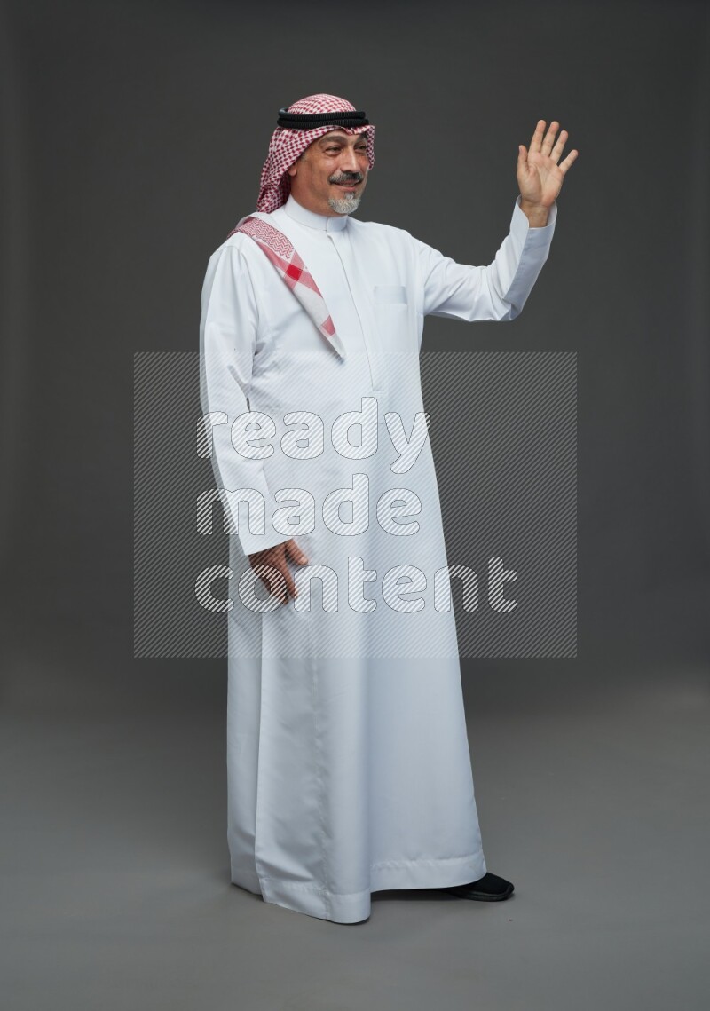 Saudi man with shomag Standing Interacting with the camera on gray background