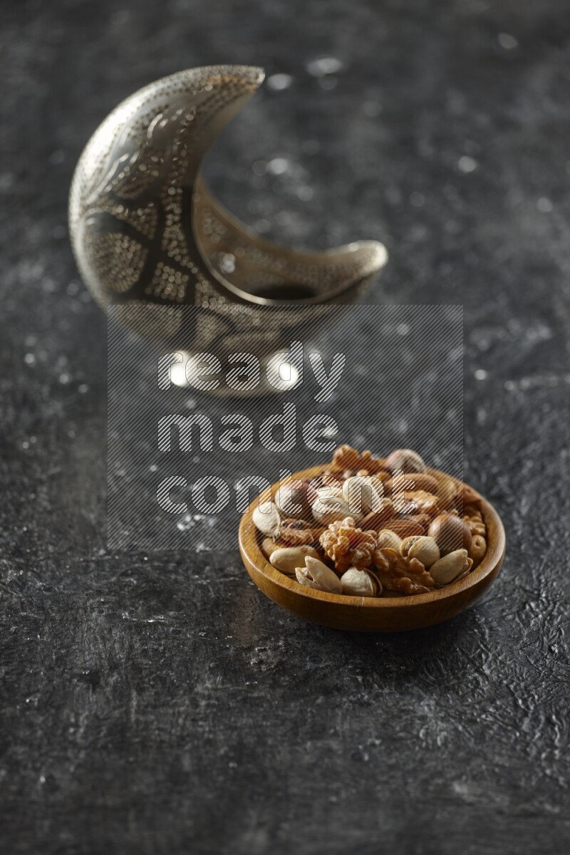 A silver lantern with different drinks, dates, nuts, prayer beads and quran on textured black background
