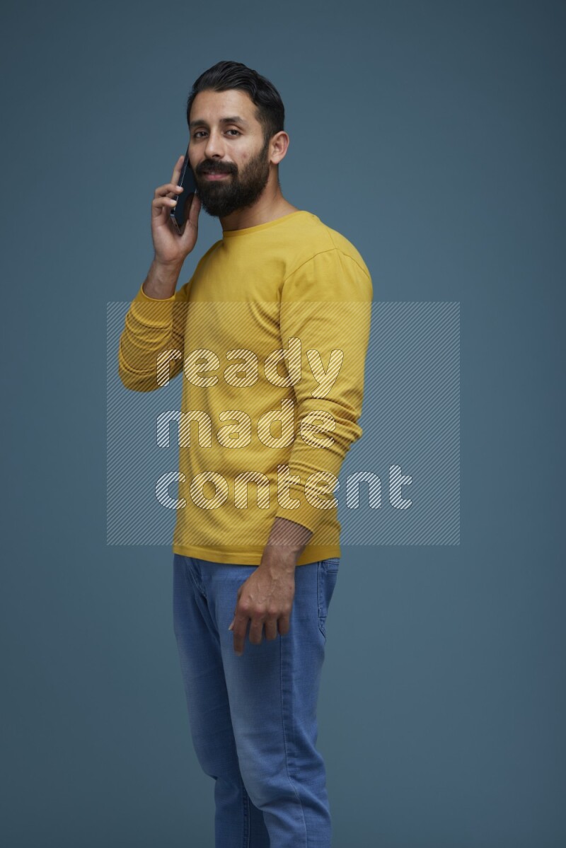 A man having a calling in a blue background wearing a yellow shirt