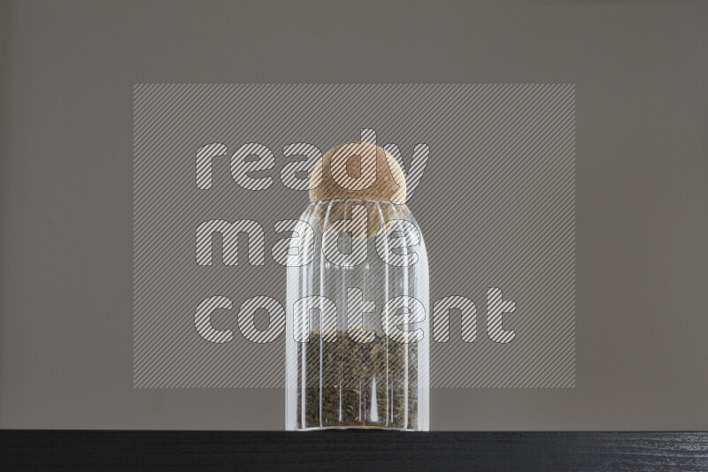Dried basil in a glass jar on black background