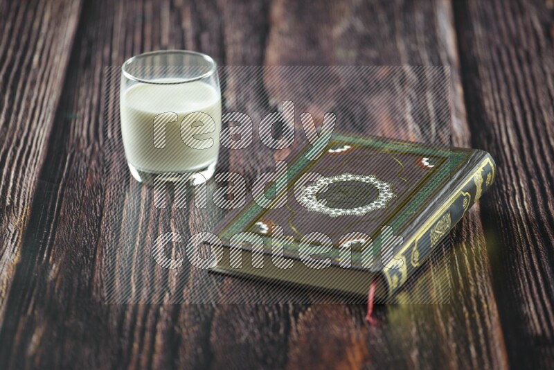 Quran with dates, prayer beads and different drinks all placed on wooden background