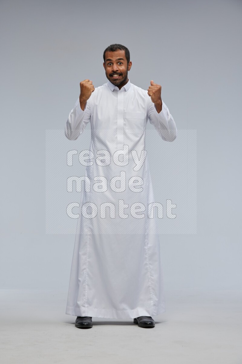 Saudi man Wearing Thob standing interacting with the camera on Gray background