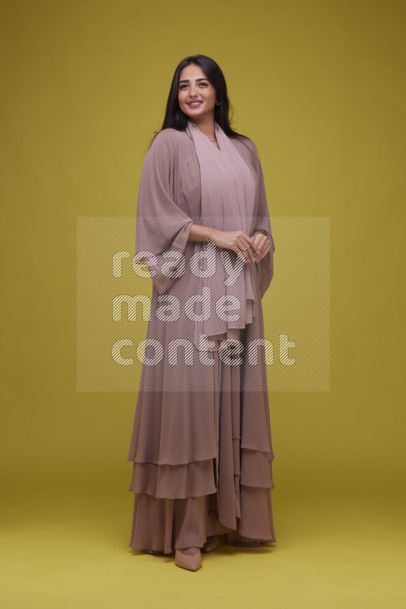 A woman Posing on a Yellow Background wearing Brown Abaya