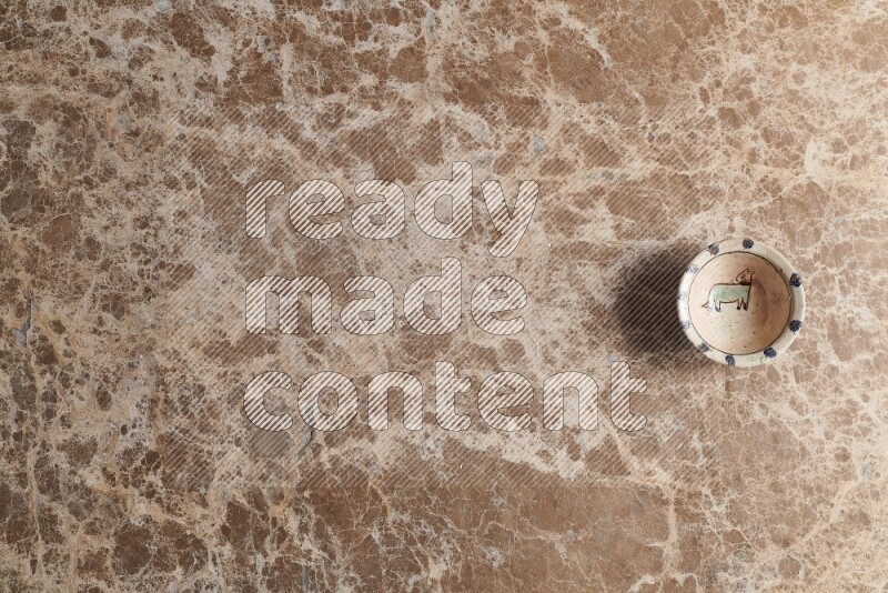 A multicolored pottery bowl on beige marble background