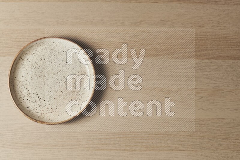 A multicolored pottery plate on light wooden background