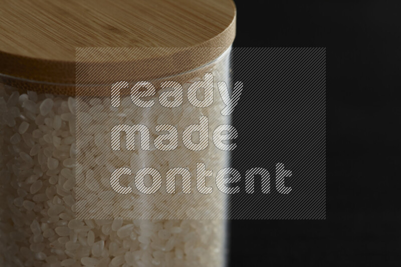 White rice in a glass jar on black background