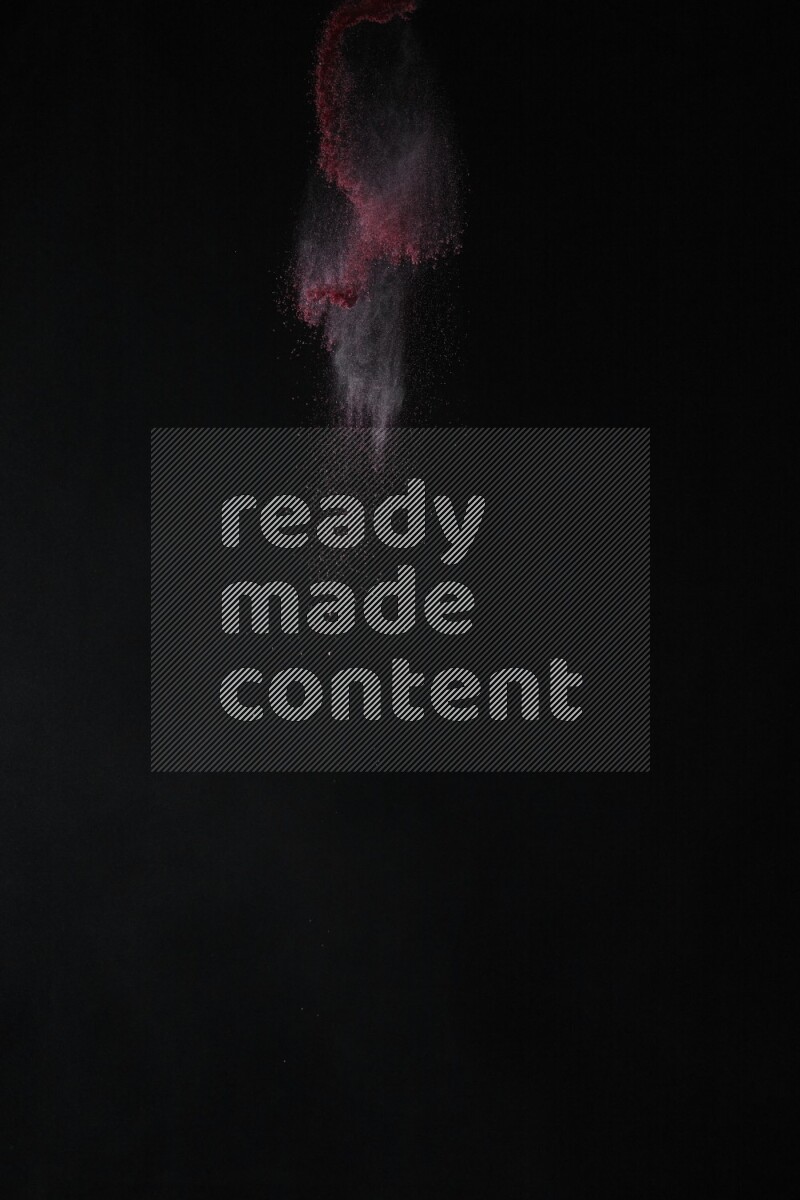 A side view of red powder explosion on black background