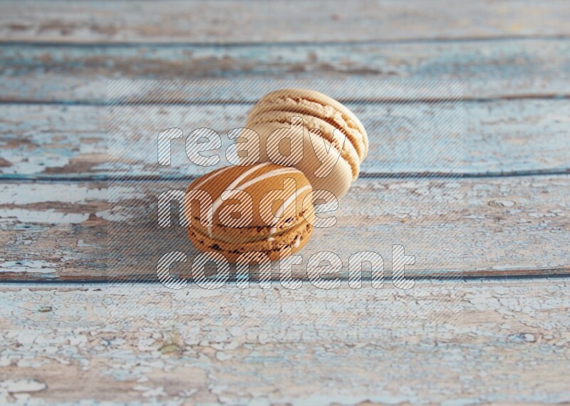 45º Shot of of two assorted Brown Irish Cream, and White Caramel fleur de sel macarons on light blue background