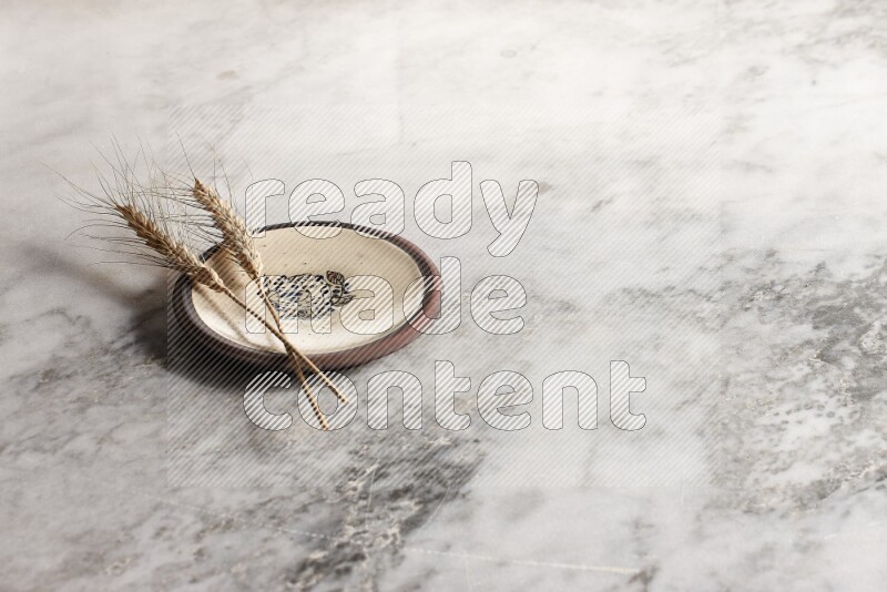Wheat stalks on decorative pottery plate on grey marble background
