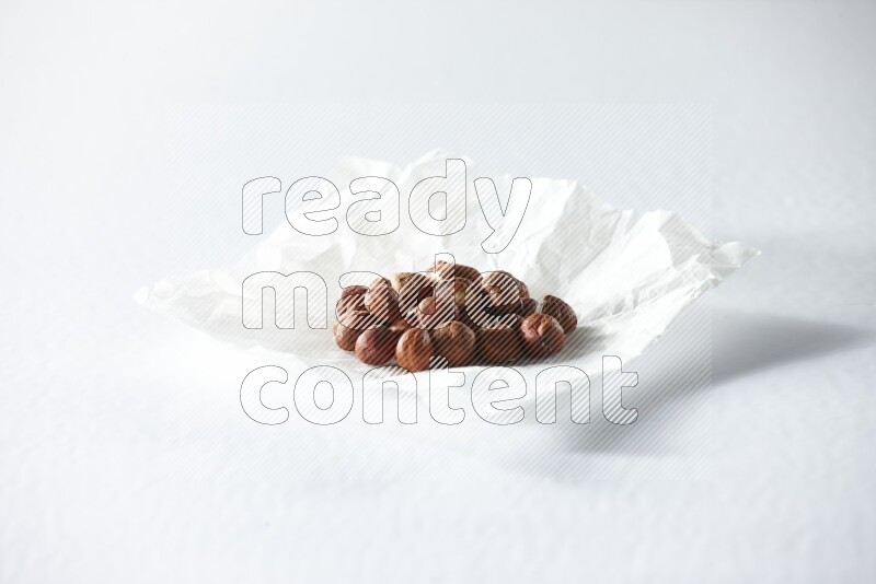 Peeled hazelnuts on a crumpled piece of paper on a white background in different angles