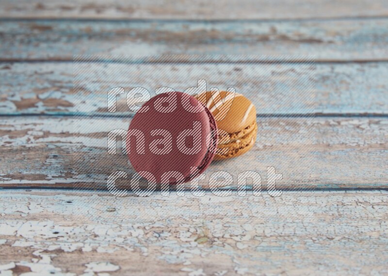 45º Shot of of two assorted Brown Irish Cream, and Red Cherry macarons  on light blue background