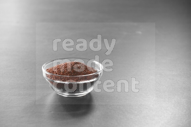A glass bowl full of garden cress on black flooring