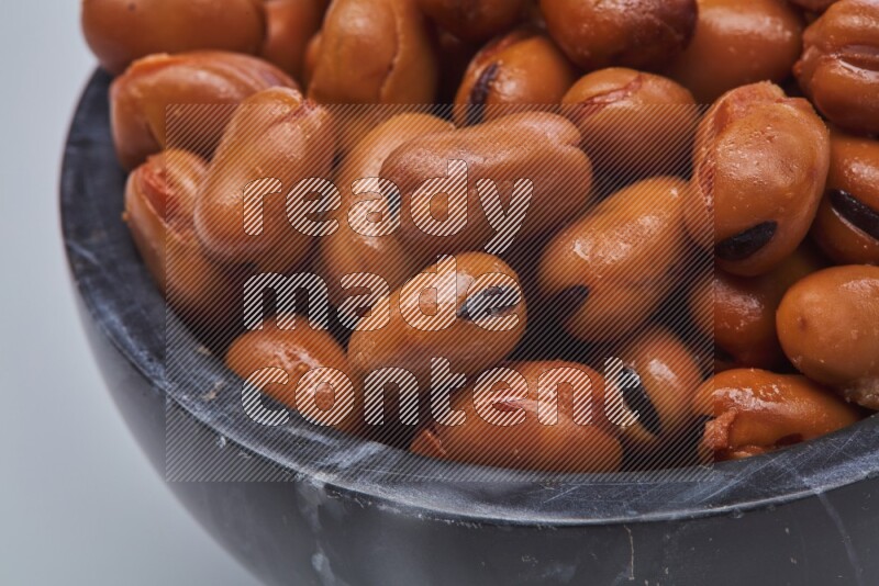 Close up shot of cooked fava beans (foul) in a container on white background