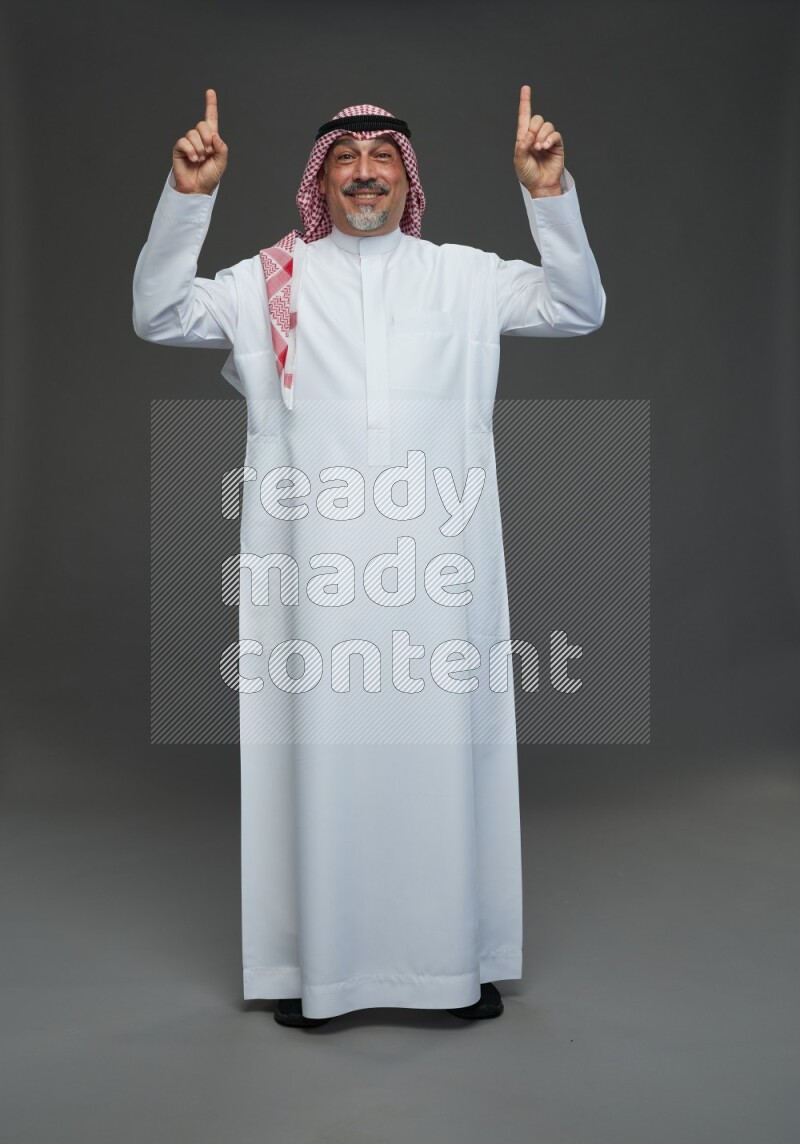 Saudi man with shomag Standing Interacting with the camera on gray background