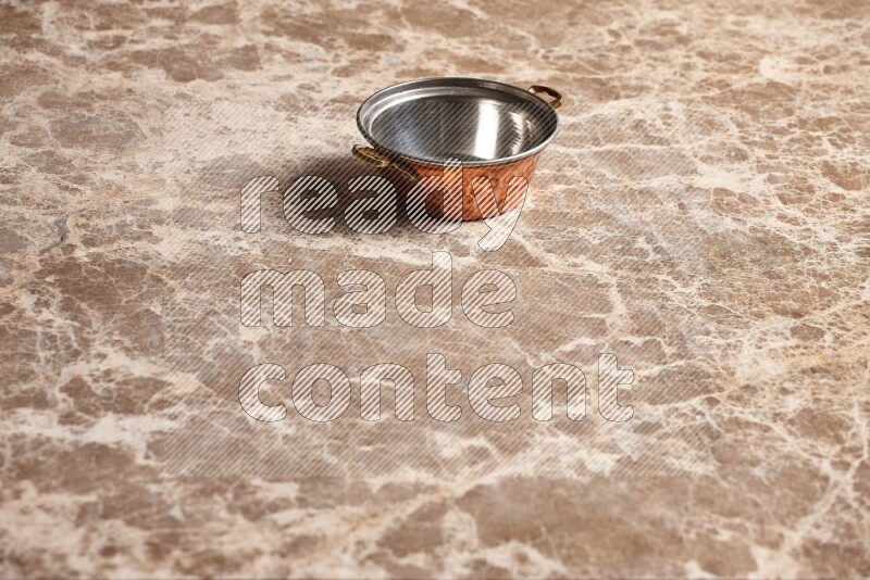 A small copper pot on beige marble background
