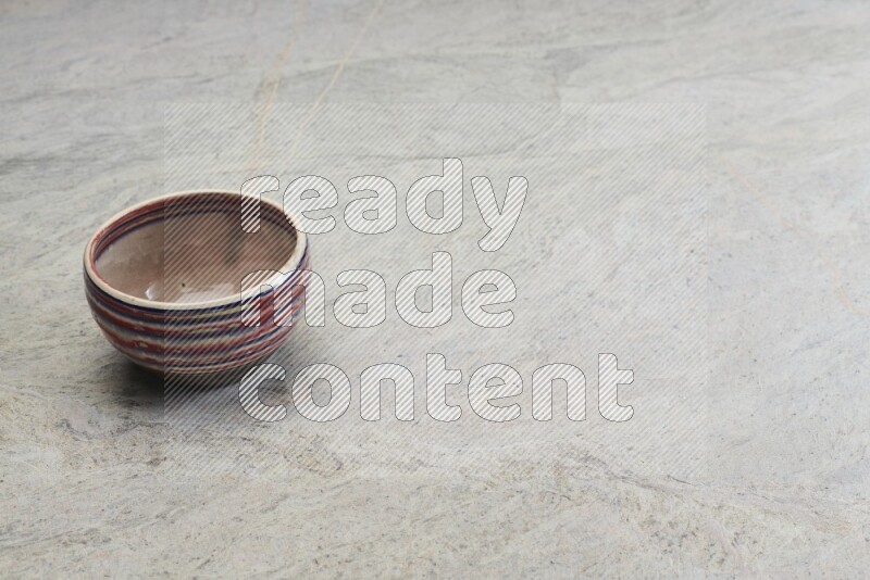A multicolored pottery bowl on grey marble background