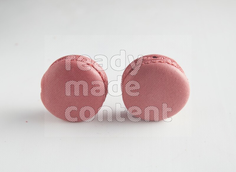 45º Shot of two Pink Raspberry macarons on white background