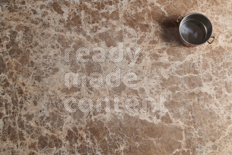 A small copper pot on beige marble background