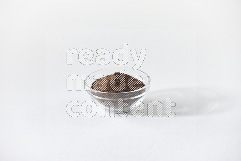 A glass bowl full of cloves powder on white flooring