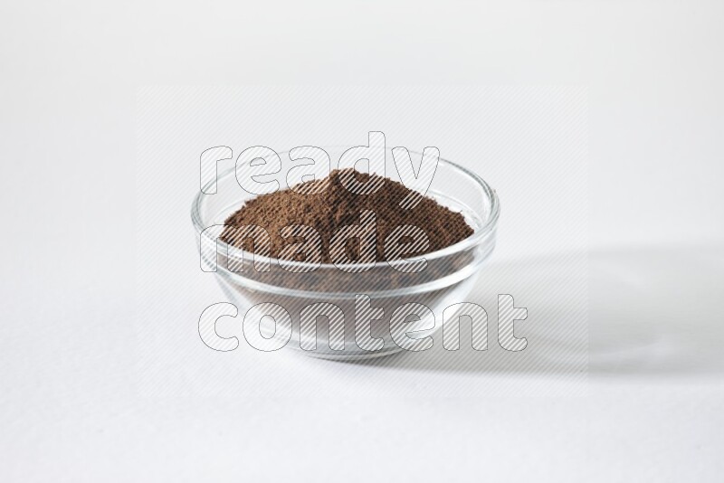 A glass bowl full of cloves powder on white flooring