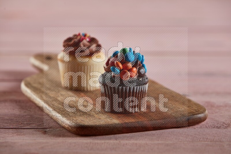 Chocolate mini cupcake topped with m&ms on a wooden board