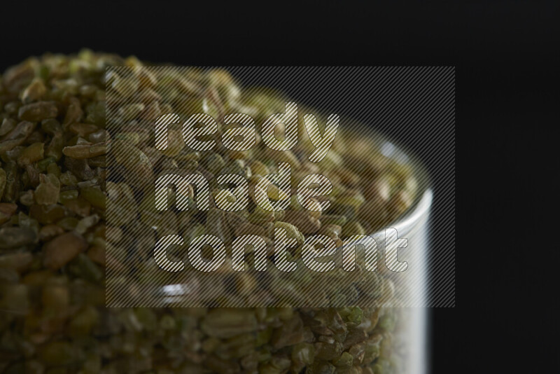 Freekeh in a glass jar on black background