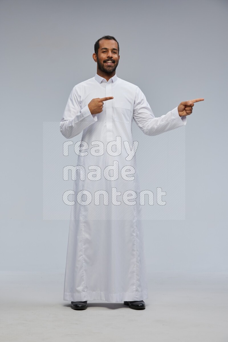 Saudi man Wearing Thob standing interacting with the camera on Gray background
