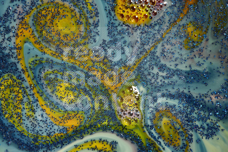 A close-up of sparkling blue glitter scattered on swirling blue and yellow background