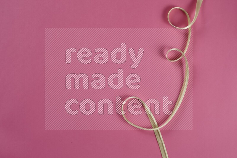 A green and pink collection of sewing and tailoring tools arranged on a pink background