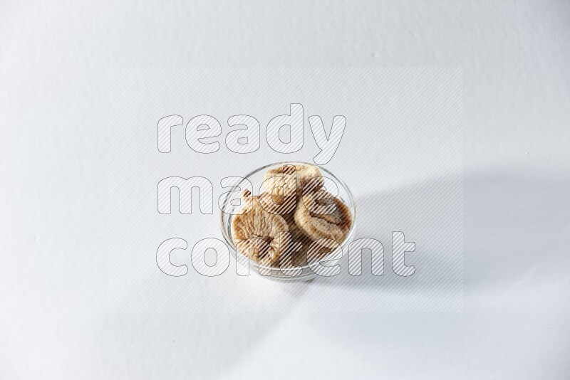 A glass bowl full of dried figs on a white background in different angles