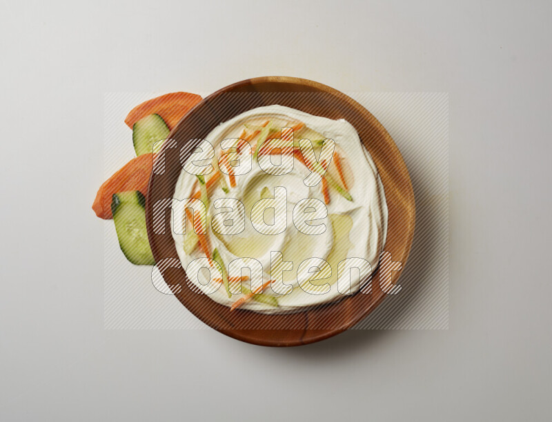 Lebnah garnished with sliced carrots & cucumber in a wooden plate on a white background