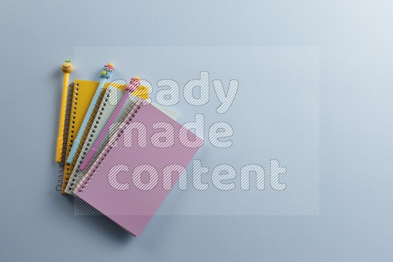 Multicolored notebooks with different school supplies on blue background