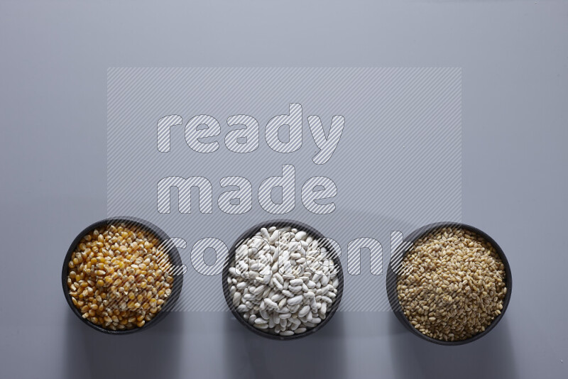 Legumes in pottery bowls on light grey background