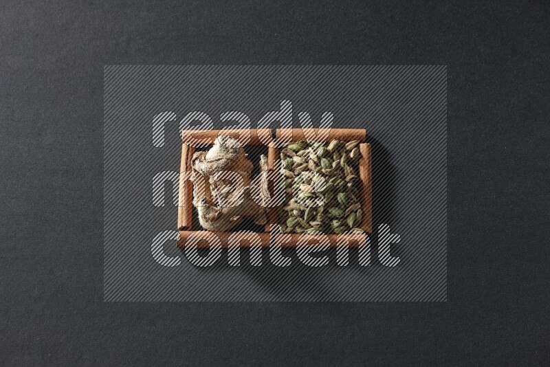 2 squares of cinnamon sticks full of cardamom and dried ginger on black flooring