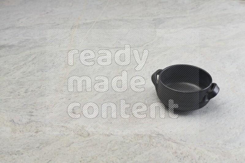 A black pottery bowl on grey marble background
