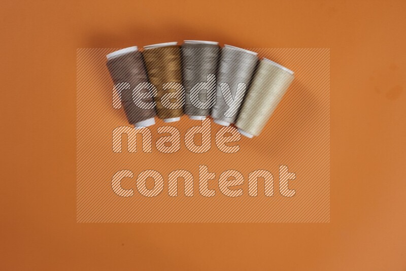 مجموعة من أدوات الخياطة والتفصيل بنية اللون على خلفية برتقالية