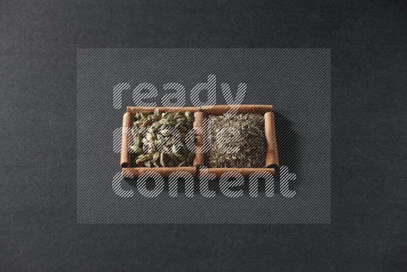 2 squares of cinnamon sticks full of cumin and cardamom on black flooring