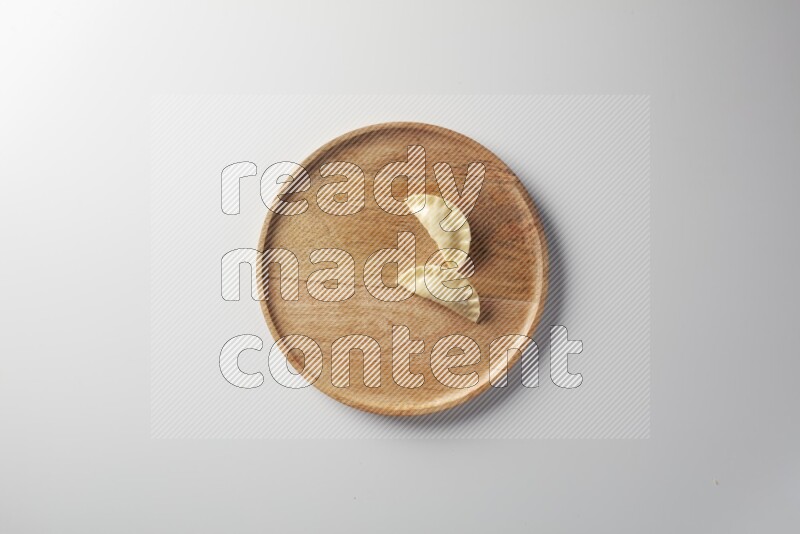 Two Sambosas on a wooden round plate on a white background