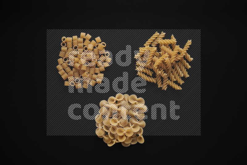 Different pasta types in bunches on black background