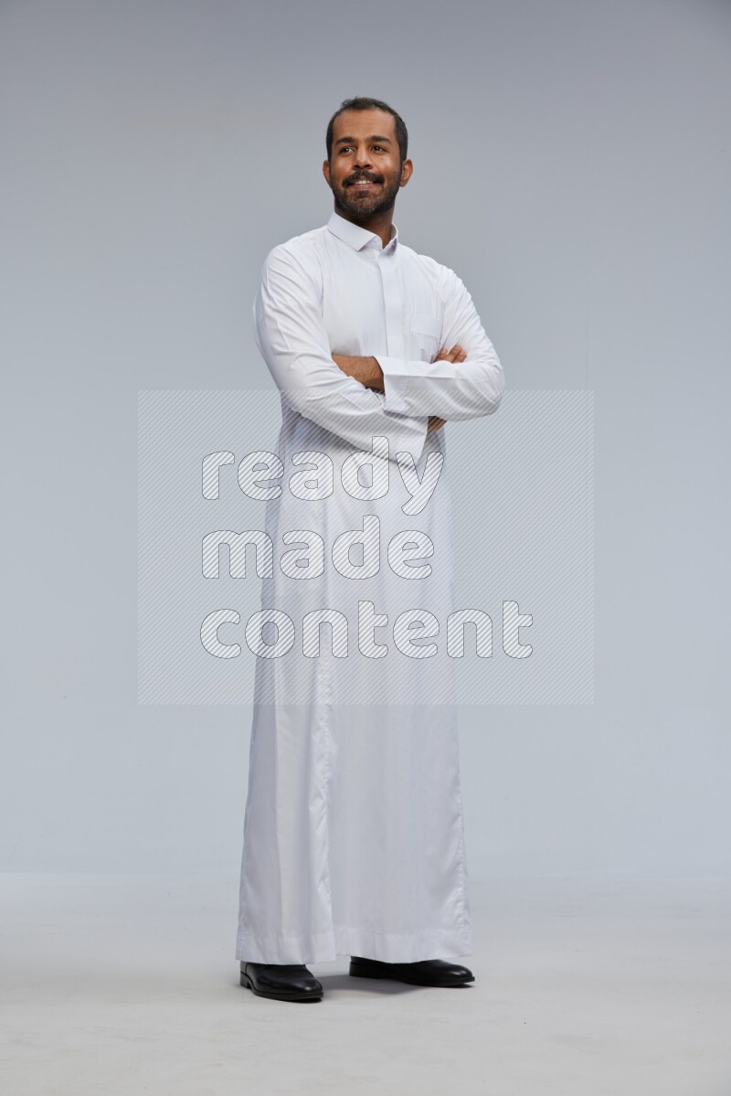 Saudi man wearing Thob standing with crossed arms on Gray background
