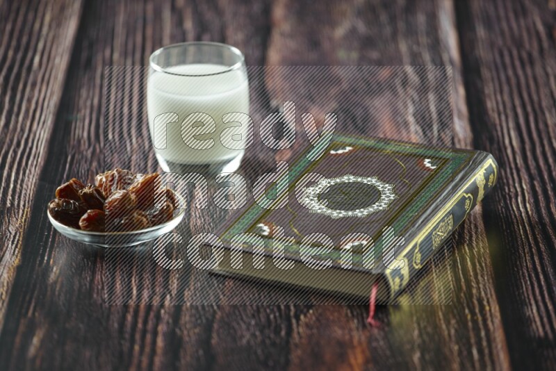 Quran with dates, prayer beads and different drinks all placed on wooden background