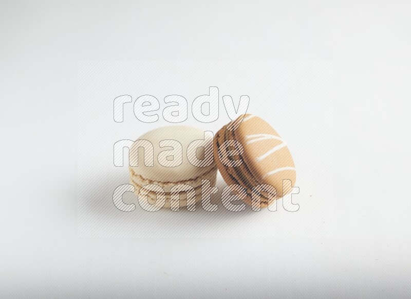 45º Shot of of two assorted Brown Irish Cream, and White Caramel fleur de sel macarons on white background