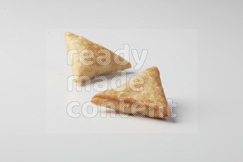 Two fried sambosas on a white background