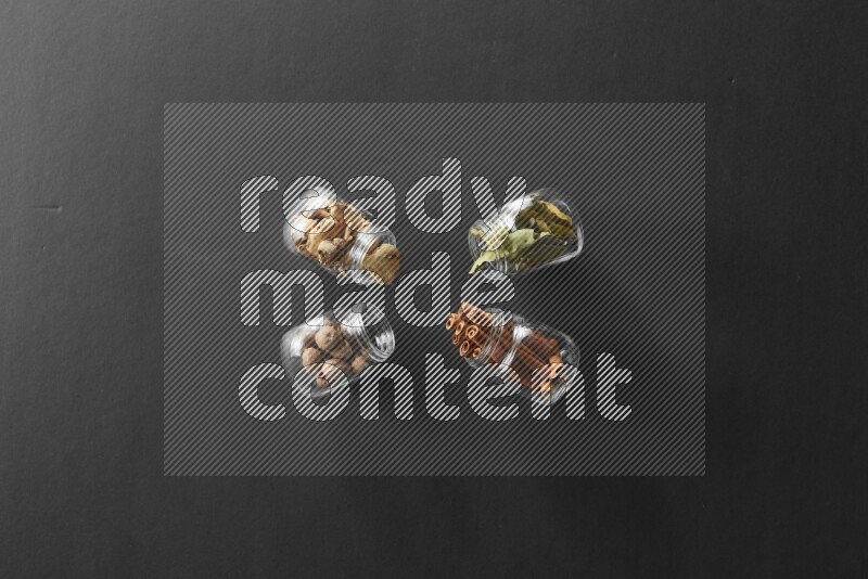 أوراق الغار وزنجبيل مجفف وقرفة وجوزة الطيب في أوعية زجاجية علي خلفية سوداء